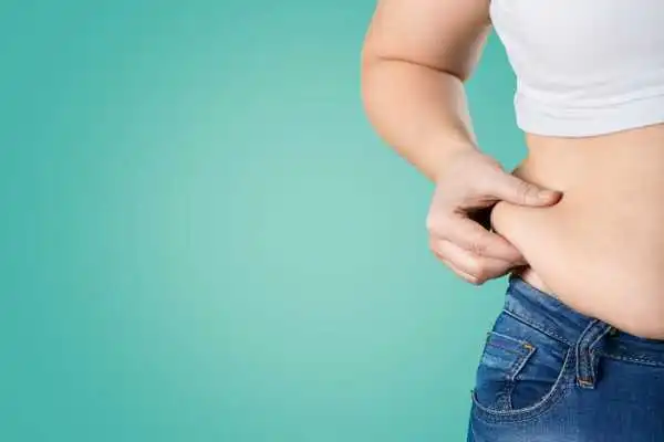 Image of woman pinching her love handles to show weight gain Bromyard