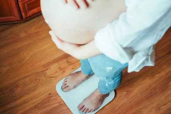 Image of woman weighing herself and experiencing weight gain through pregnancy Bromyard